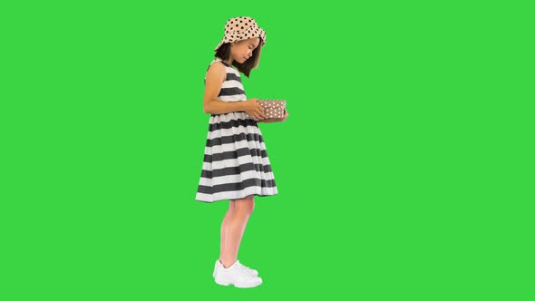 Asian Girl Opening a Box with a Present on a Green Screen, Chroma Key.