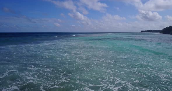 Natural birds eye tourism shot of a white sand paradise beach and blue ocean background in hi res 4K