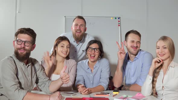 Happy Young People Are Sitting at Office Room Looking at Camera Sway Hands