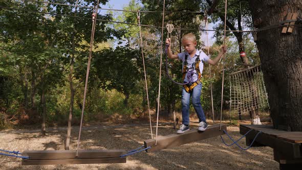 Boy Walks By Rope at Sunny Summer Day in Adventure Playground.