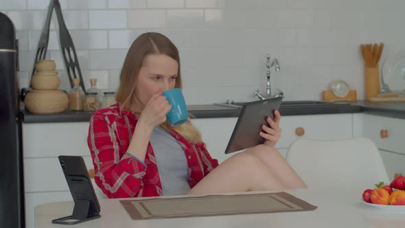 Positive Middle Aged Woman with Cup of Coffee Browsing Online on Tablet Pc