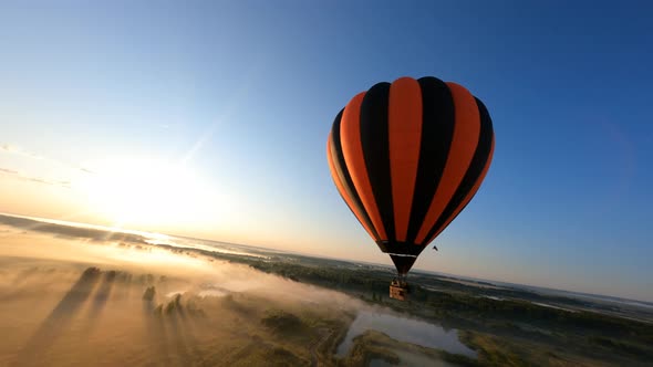 Orange hot air balloons floating above field in the beautiful summer sunrise