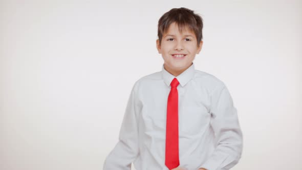 School Kid in Red Tie Smiling on White Background Looking Upwards Pointing at Camera