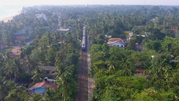 Aerial Shot the Old Train Rides Through the Tropics with Palm Trees and Villas