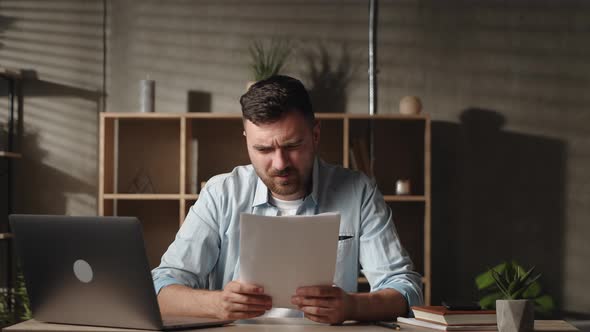 Frustrated Young Man Looking Through Paper Document Feeling Confused of Getting Bank Loan Mortgage