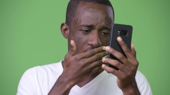 Young African Man Looking Shocked While Using Phone