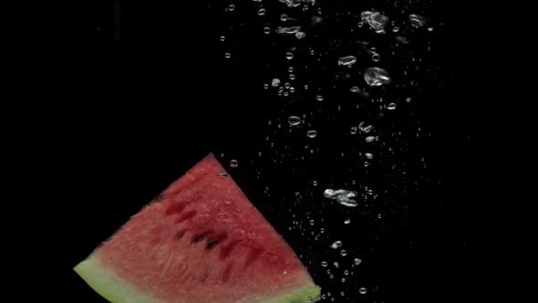 Slow Motion Slice Watermelon Falling Into Transparent Water on Black Background