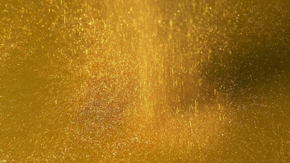 Sparkly Gold Powder Pours Onto Gold Surface