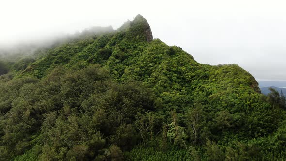 Drone floating to the peak of a hawaiian mountain on oahu as rain clouds cover the island