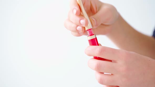 Female Hands Holding Lip Gloss Against White Background