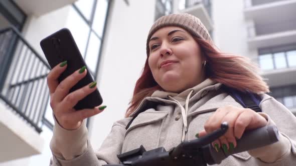 Closeup Lowangle View of Delivery Woman with Thermo Backpack Using Navigation App on Mobile Phone