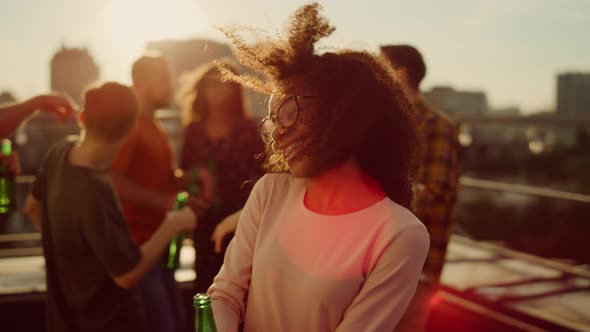 Afro Girl Dancing with Bottle Beer in Hand at Party