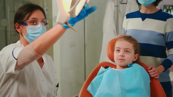 Woman Stomatologist Technician Lighting the Lamp for Examining Little Patient