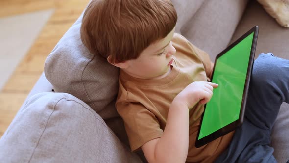 Preschool Caucasian Boy Tabs on the Green Screen of Tablet PC