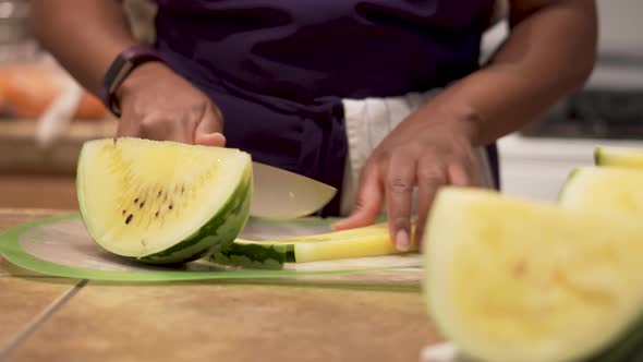 Close Up, chopping up pieces of yellow watermelon in a kitchen