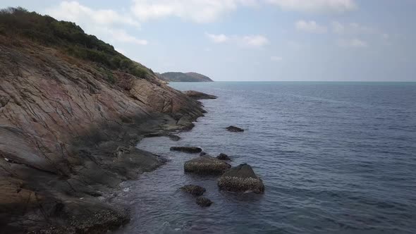 Aerial: low alltitude landscape shot over the rocks, steep shore and the ocean. The drone flies smoo