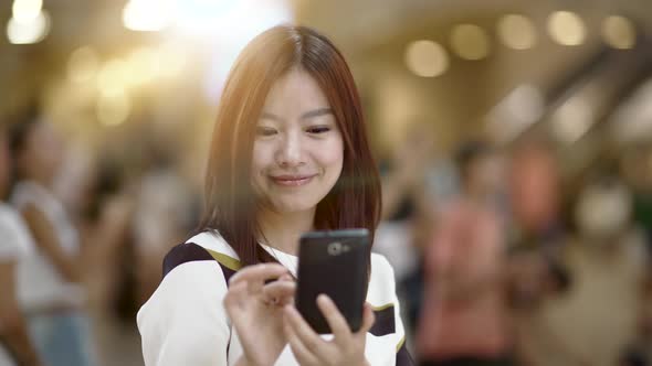 Beautiful Young Asian Female Browsing the Internet on Mobil Phone