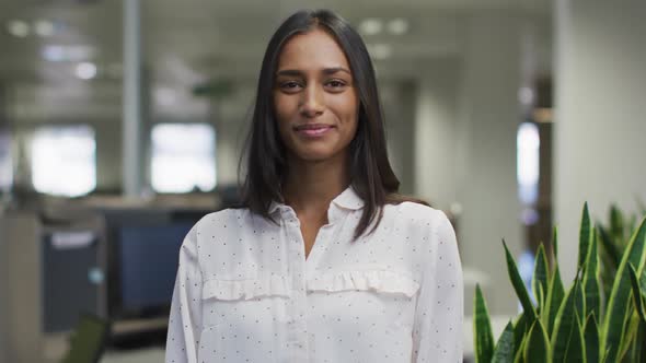 Video of happy biracial woman looking at camera in office