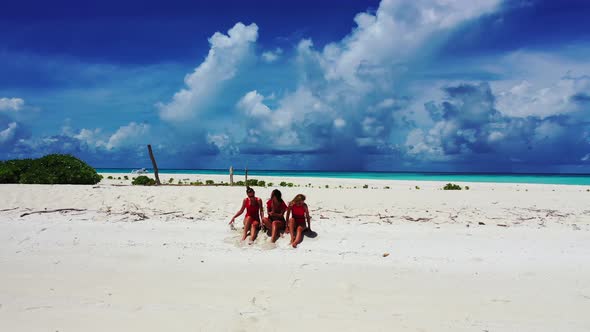 Young smiling ladies relaxing having fun on beach on paradise white sand and blue 4K background