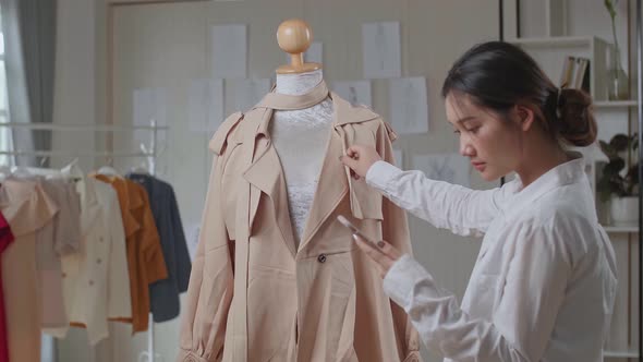 Young Asian Woman Fashion Designer Looking His Phone With Clothes On Mannequin Model