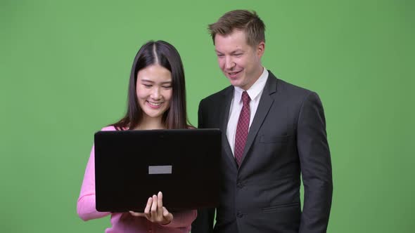 Young Asian Woman and Young Businessman Using Laptop Together