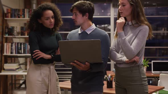 Creative businesspeople discussing over laptop in modern office