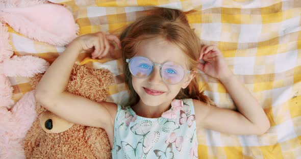 A Little Girl of 67 Years with Glasses Rests and Sends Greetings with Her Hand