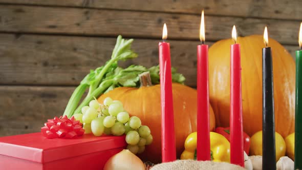 Composition of seven lit candles and halloween pumpkins, present and vegatables
