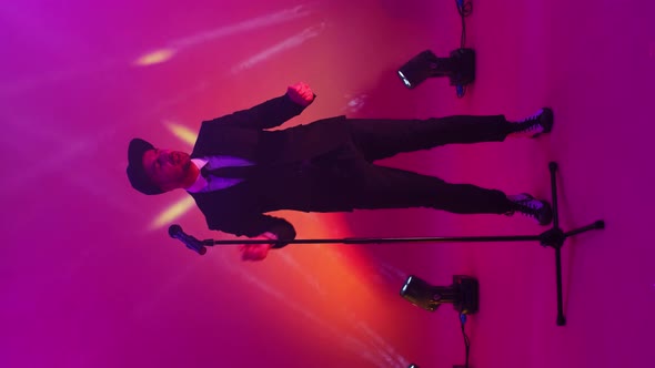 Vertical Video. Neon Lights and Strobe Lights a Man Sings in and Dances Into a Microphone. Funny