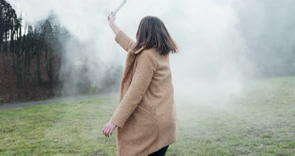 Woman Makes Emergency Flare Signal with White Smoke. Hipster Pretty Girl with Smoke Bomb