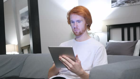 Online Shopping on Tablet PC by Sitting Redhead Man