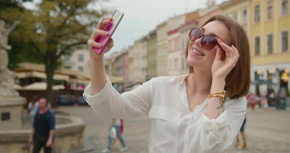 A Girl is Taking a Selfie When Standing in the Central Square