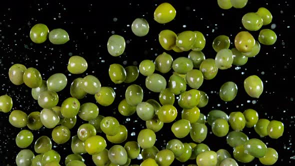 Super Slow Motion Shot of Flying Olives and Water Side Splash Isolated on Black at 1000 Fps