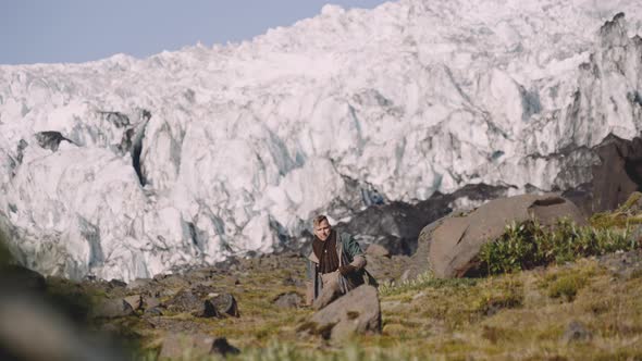 Traveller Carrying Guitar Case On Rocky Hill Next To Glacier