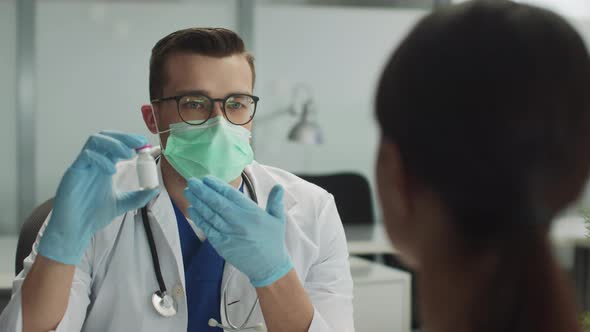 A Young Doctor in the Clinics Office Explains to a Patient the Benefits of a New Coronavirus Vaccine