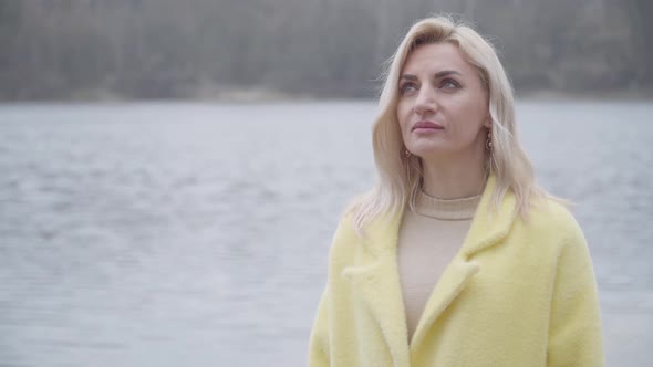 Portrait of Positive Blond Caucasian Woman Standing on Riverbank and Looking Away. Smiling Adult