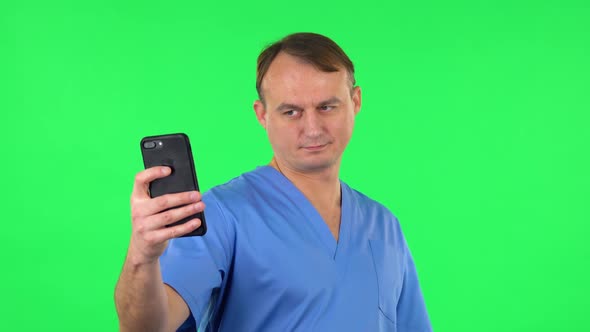 Medical Man Makes Selfie on Mobile Phone Then Looking Photos on Green Screen.