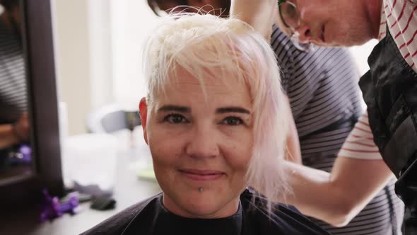 Front view woman having her hair dry by a hairdresser