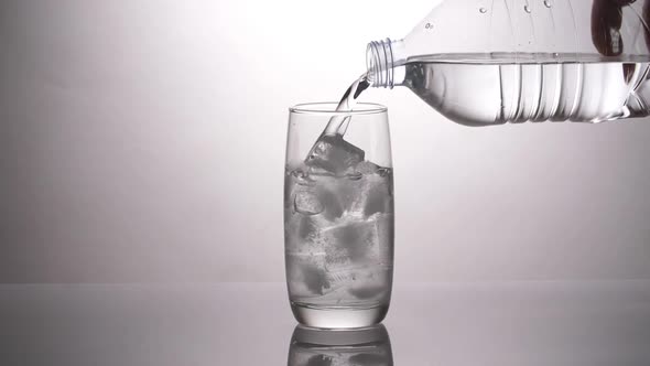 Water Pours Into A Glass With Ice Cubes