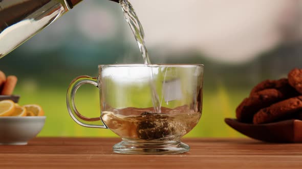 Pouring Hot Water Into Teapot with Teabag on a Wooden Table