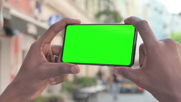 African Man Looking at Smartphone with Green Chroma Screen