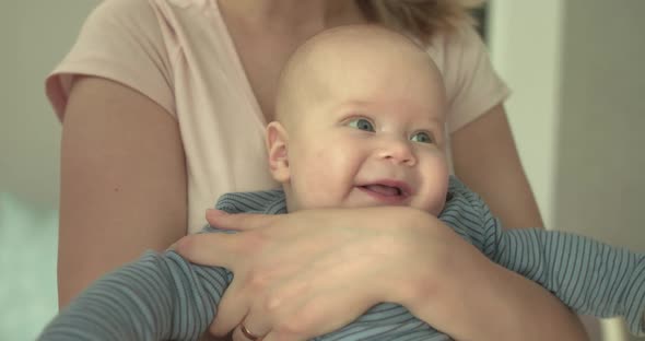 Portrait of Funny Smiling Baby on Mother's Hands