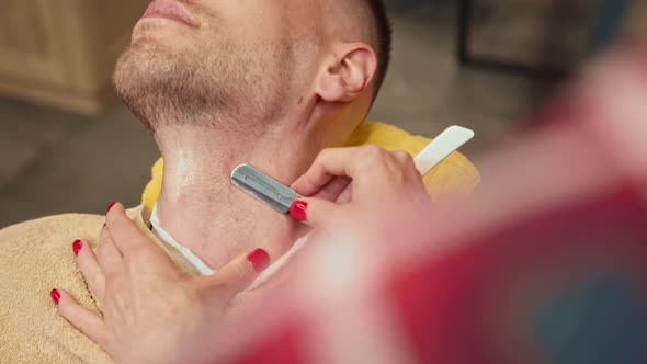 Barbershop: a woman barber shaves a man using a straight razor