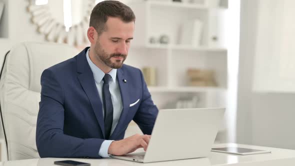 Serious Businessman with Laptop Looking at the Camera