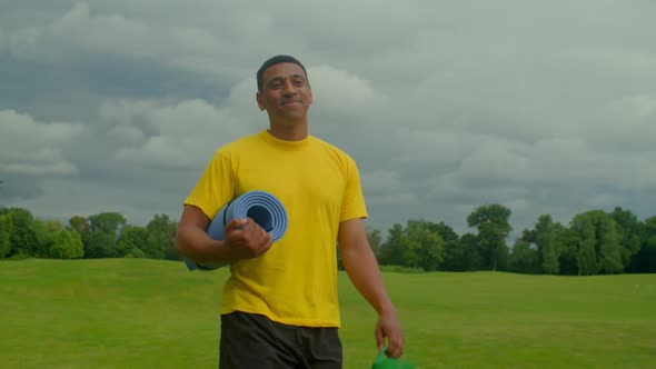 Sporty Fit African American Man with Yoga Mat Going for Outdoor Fitness Workout