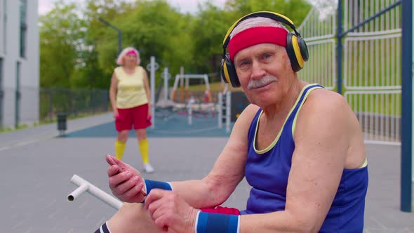 Senior Man After Sport Training Listening Music From Mobile Phone Wearing Headphones on Playground