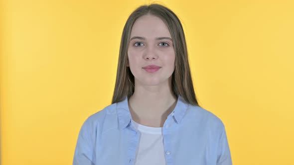 Inviting Casual Young Woman Pointing Finger, Yellow Background