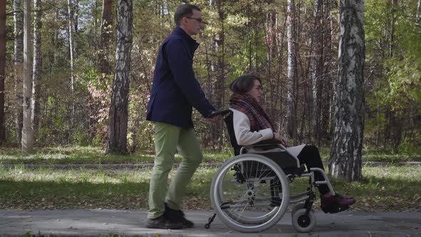 Woman on wheelchair walking with boyfriend
