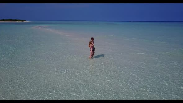 Romantic couple in love on marine island beach vacation by blue water with white sand background of 