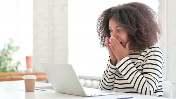 Excited African Woman Celebrating Success on Laptop 